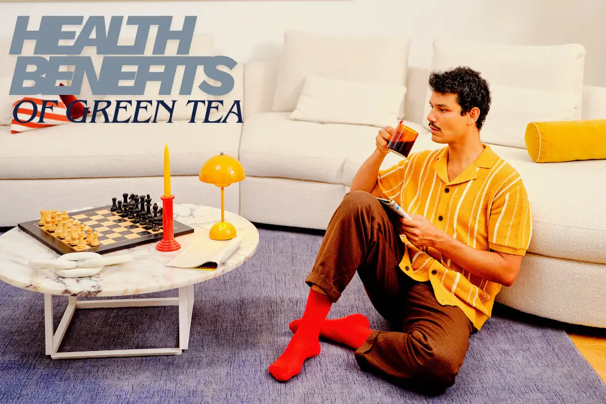 Man sitting on the floor drinking green tea with text “Health Benefits of Green Tea.”